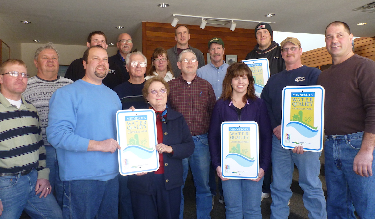 Group of farmers posing for picture holding signs for their water quality certification