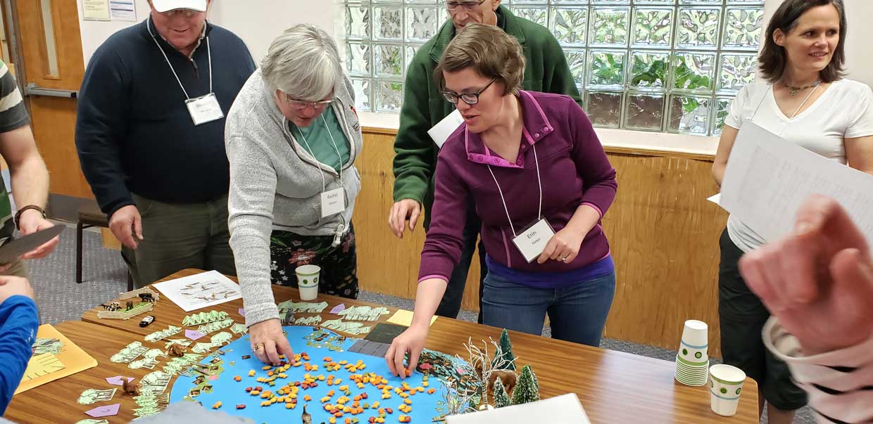 two women moving goldfish crackers on a paper display of a lake